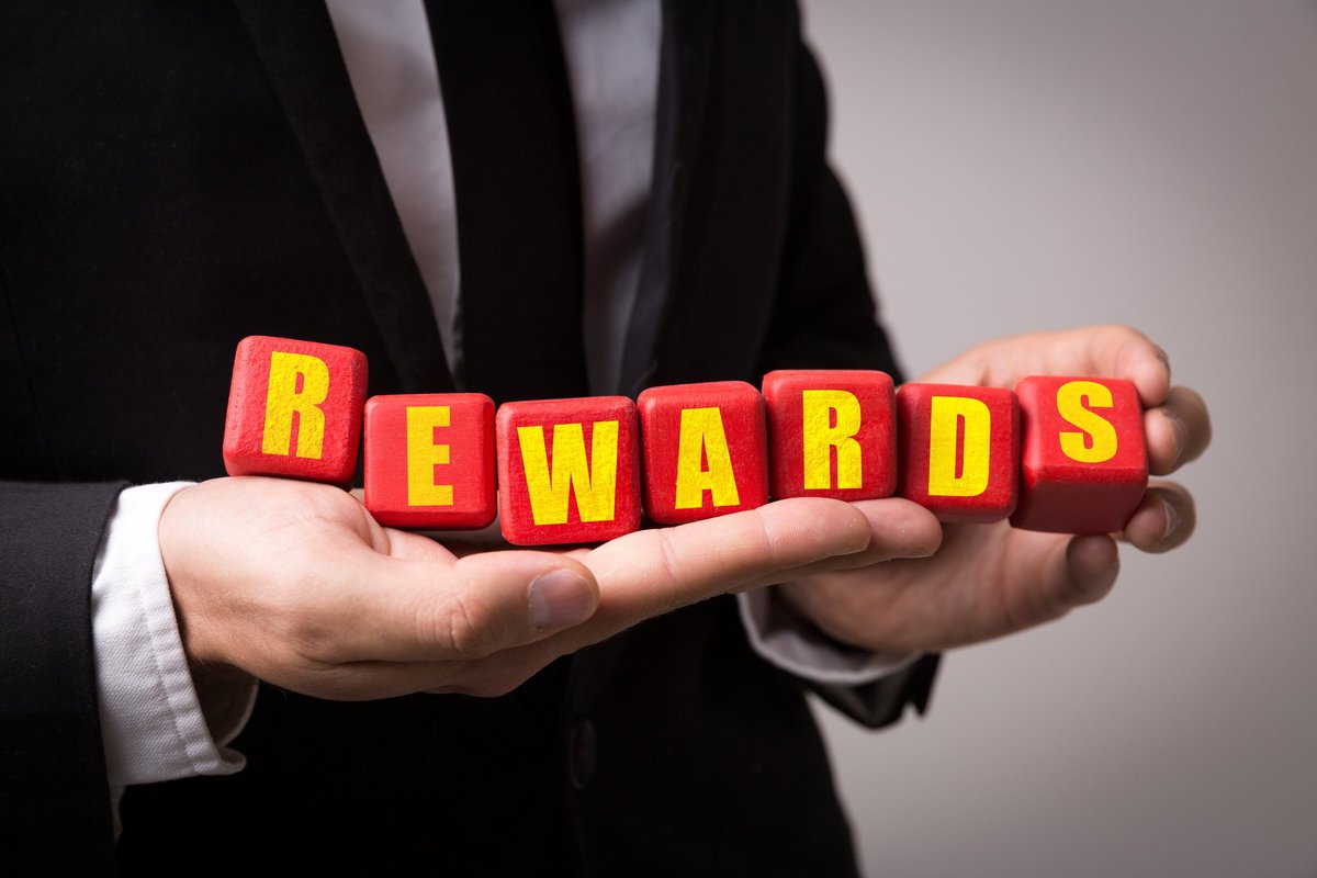Man in suit holding letter blocks that spell out "rewards"
