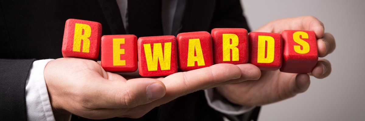 Man in suit holding letter blocks that spell out "rewards"