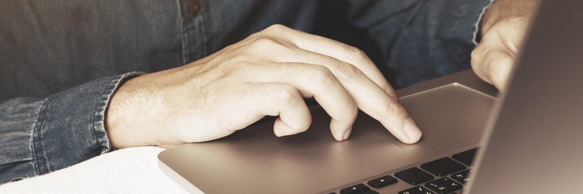 Man typing on laptop next to iPhone