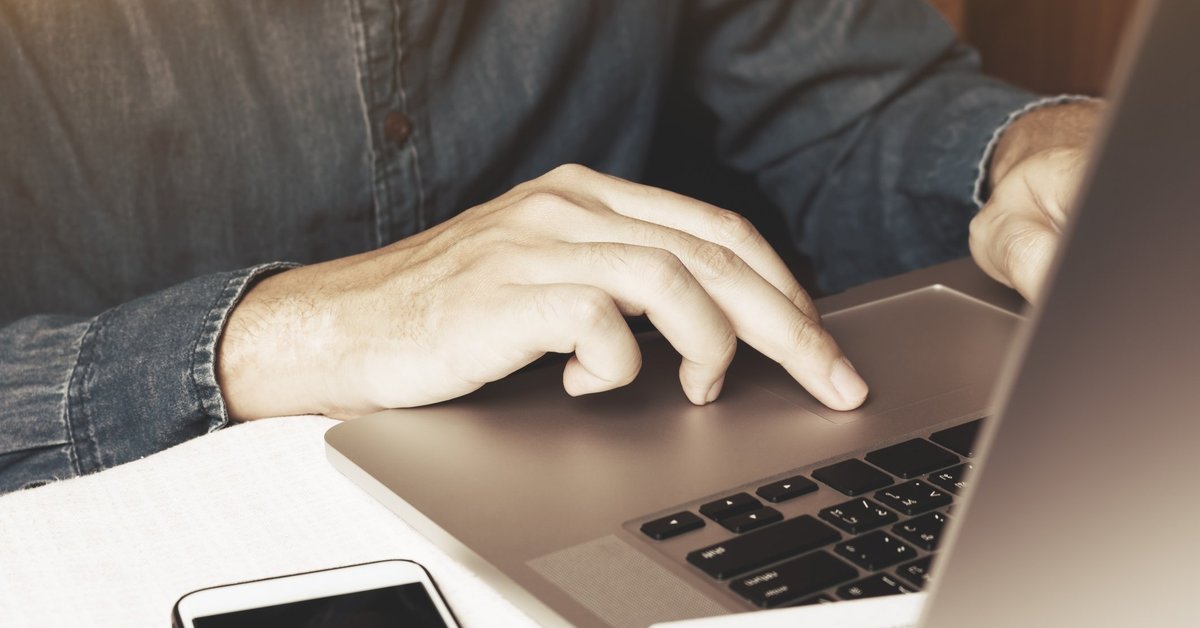 Man typing on laptop next to iPhone