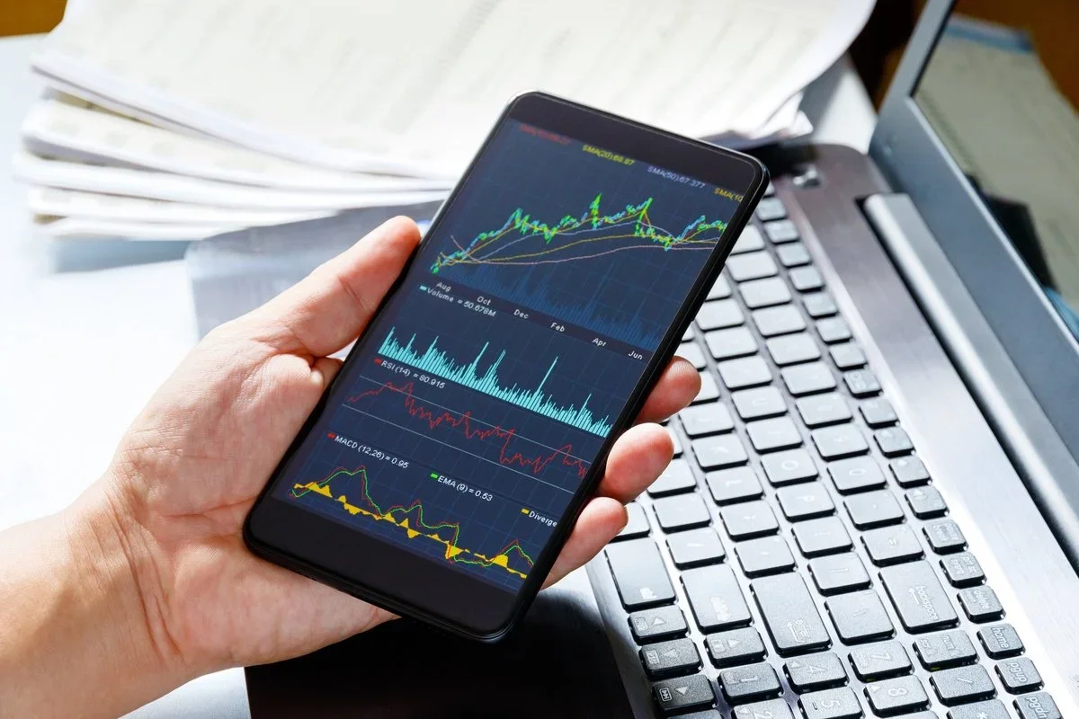 Someone holds a phone with a stock app on the screen.