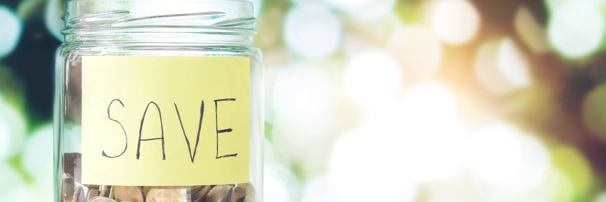 Jar of coin savings and piles of coins outside the jar.