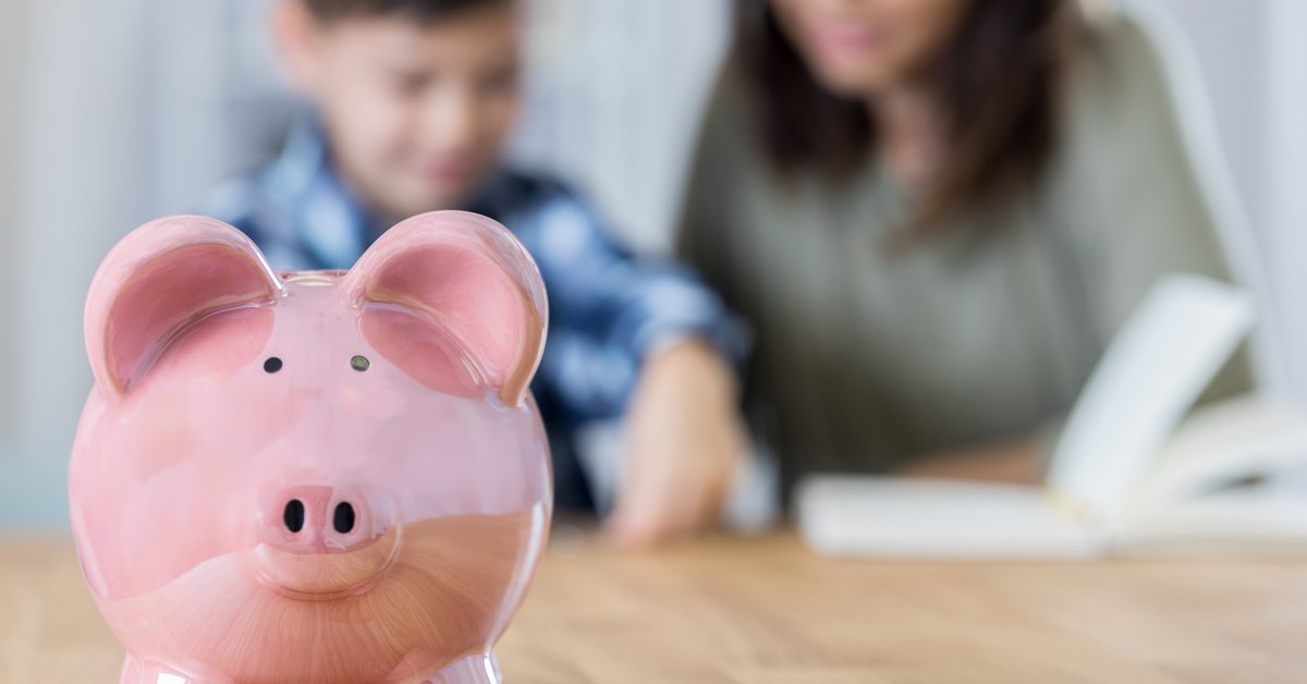 A piggy bank with a mother reading to her son in the background.