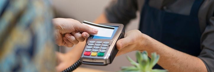 Someone hands a credit card to a cashier.