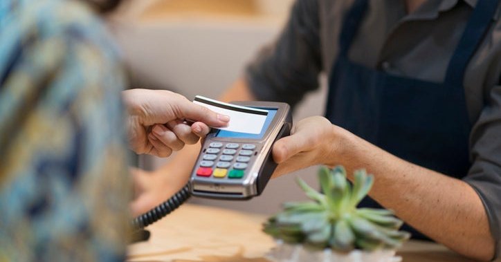 Someone hands a credit card to a cashier.