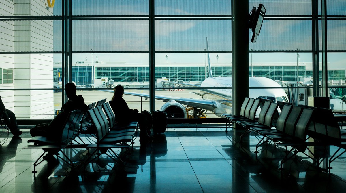 People sitting in airport with plane outside window