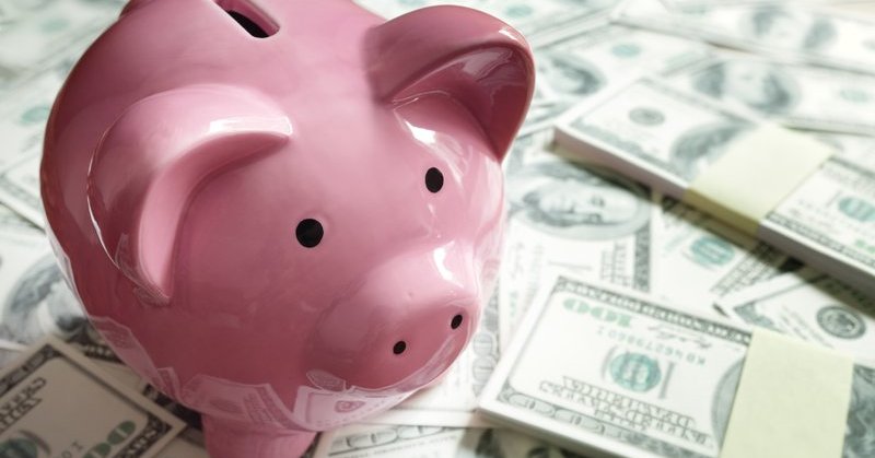 Piggy bank surround by cash stacks.