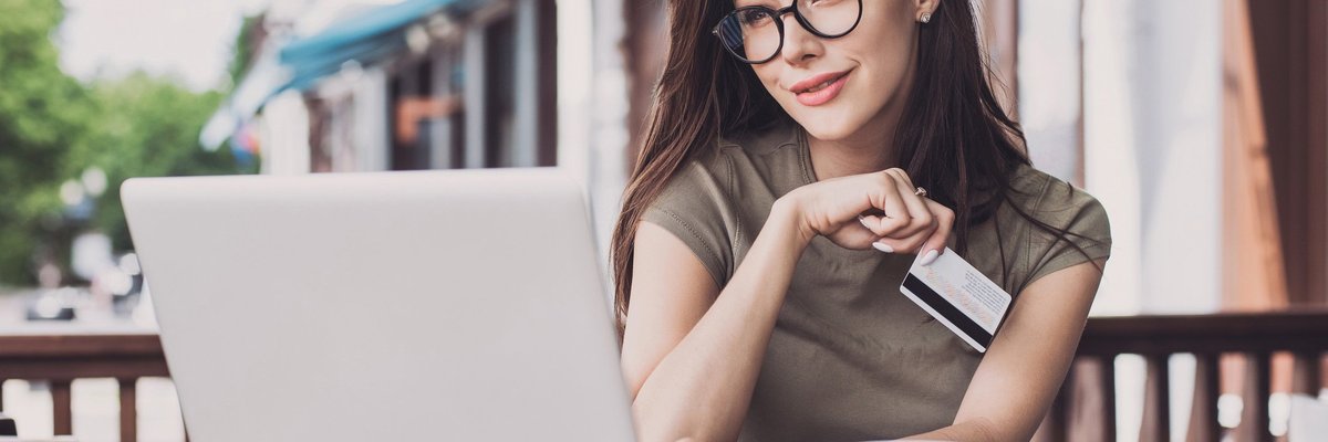 Woman sitting at outdoor cafe with laptop and credit card
