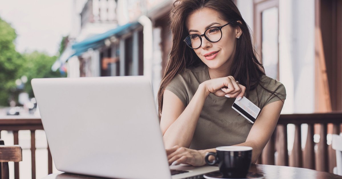 Woman sitting at outdoor cafe with laptop and credit card