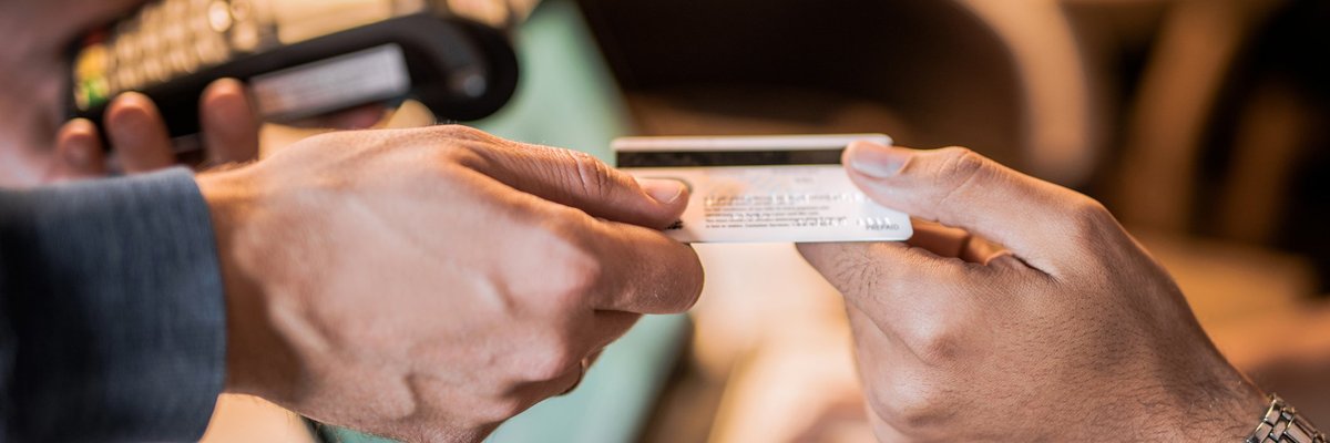 One hand passing a credit card to another hand.