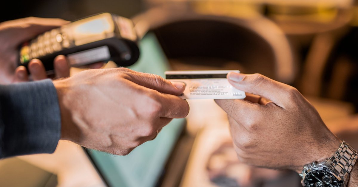 One hand passing a credit card to another hand.