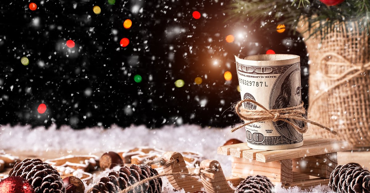 A 100-dollar bill tied with a thin rope amid snow, pine cones, and Christmas ornaments.