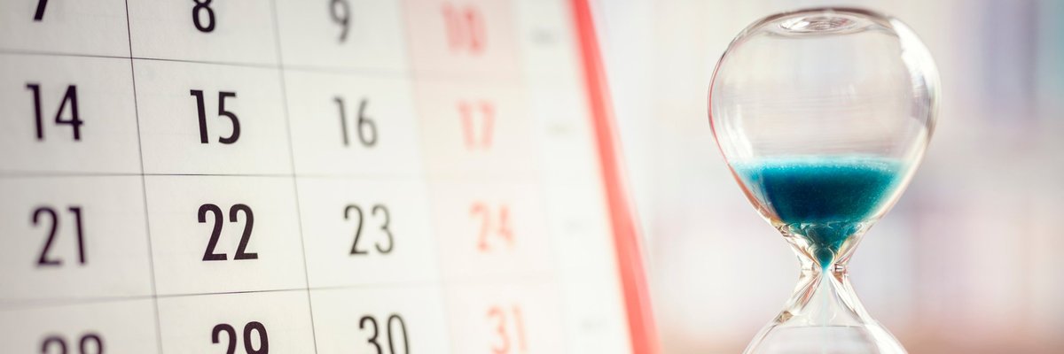 Hourglass full of blue sand next to a calendar