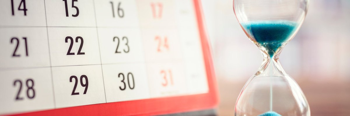 Hourglass full of blue sand next to a calendar