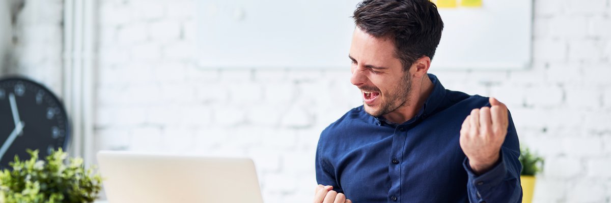 Man sitting at a desk celebrating with a fist pump