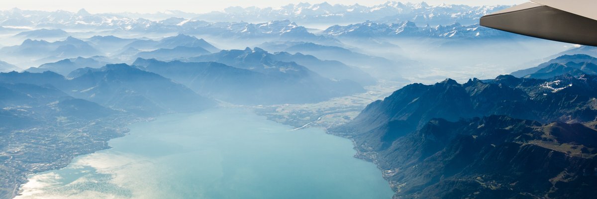 Airplane wing flying over mountains and lakes