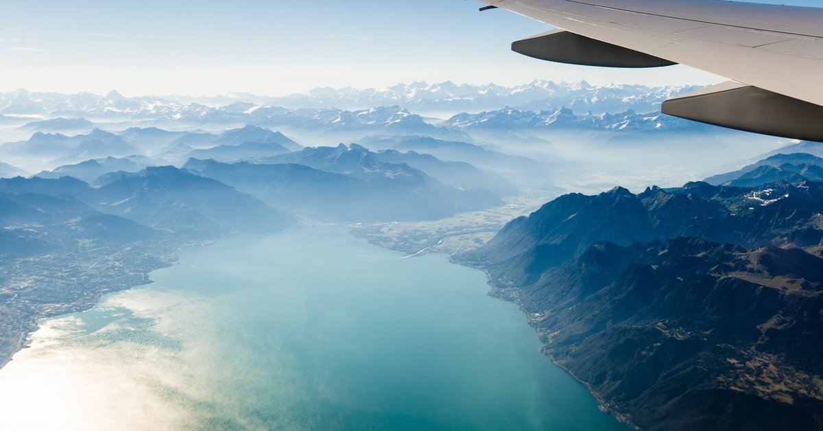 Airplane wing flying over mountains and lakes