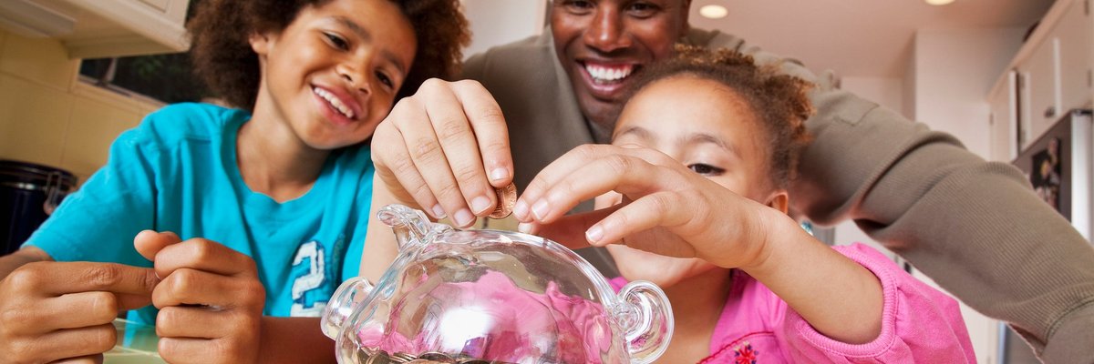 A parent watches their children put coins into a piggy bank at home.