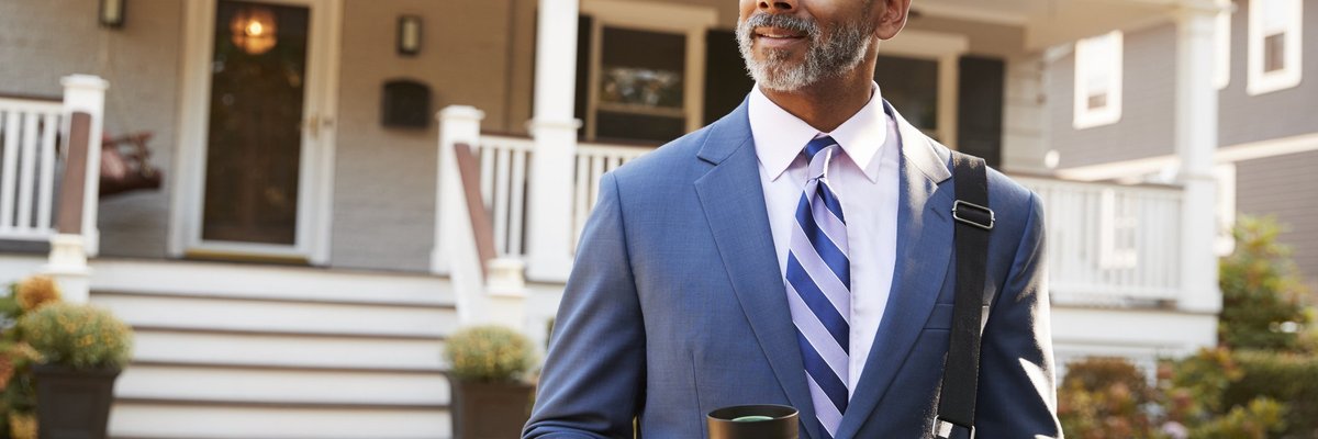 Middle-aged man in suit confidently leaving his enormous house in the morning.