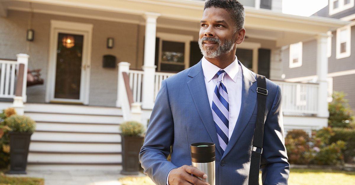 Middle-aged man in suit confidently leaving his enormous house in the morning.