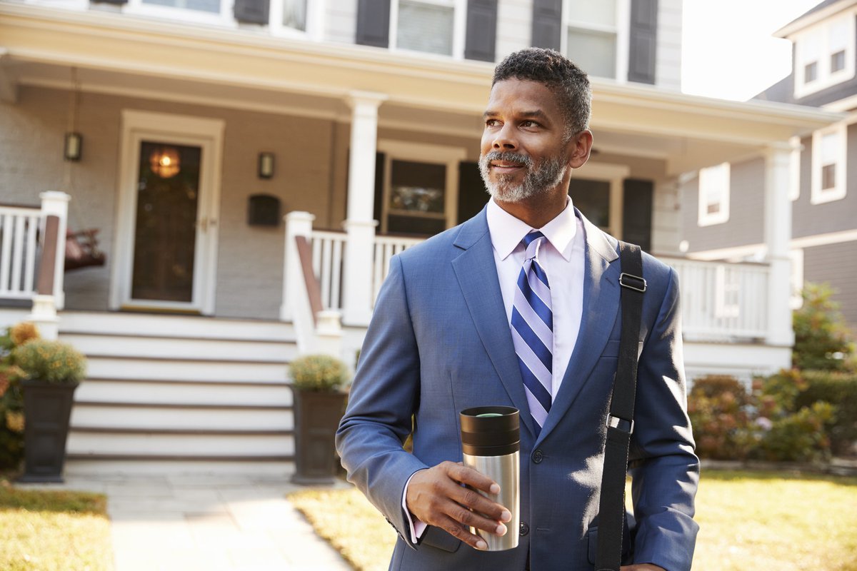 Middle-aged man in suit confidently leaving his enormous house in the morning.