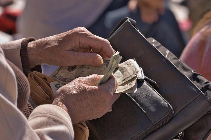 Older person counts dollar bills from their purse.