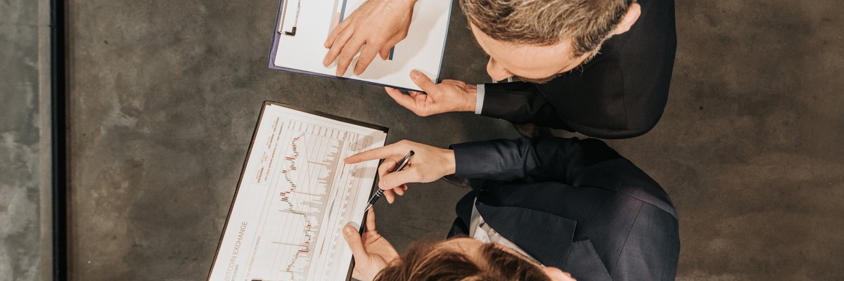 High angle view of two business workers cooperating while working on bitcoin development diagram in the office.