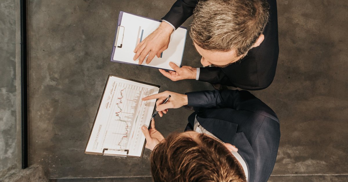 High angle view of two business workers cooperating while working on bitcoin development diagram in the office.