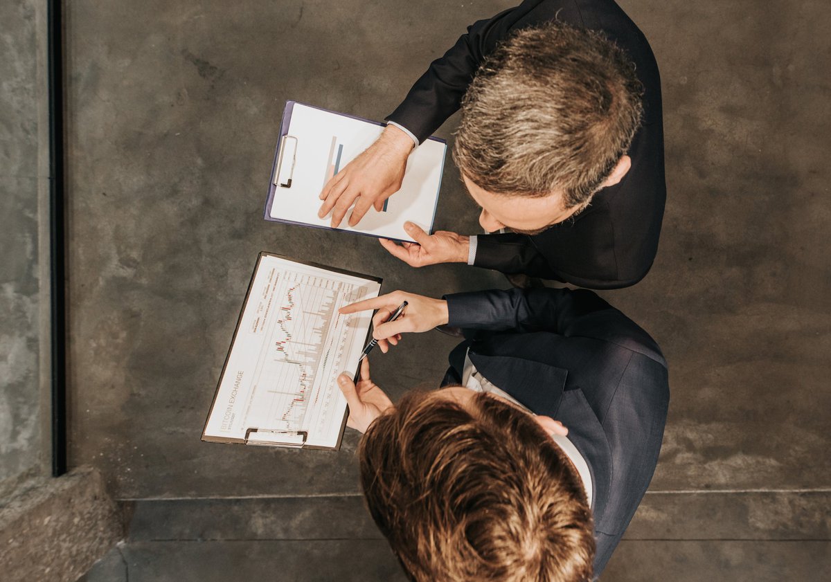 High angle view of two business workers cooperating while working on bitcoin development diagram in the office.