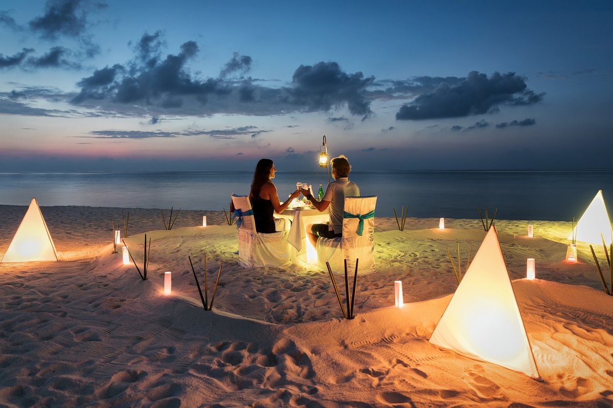 Couple toasting at an isolated restaurant-style table on the beach.