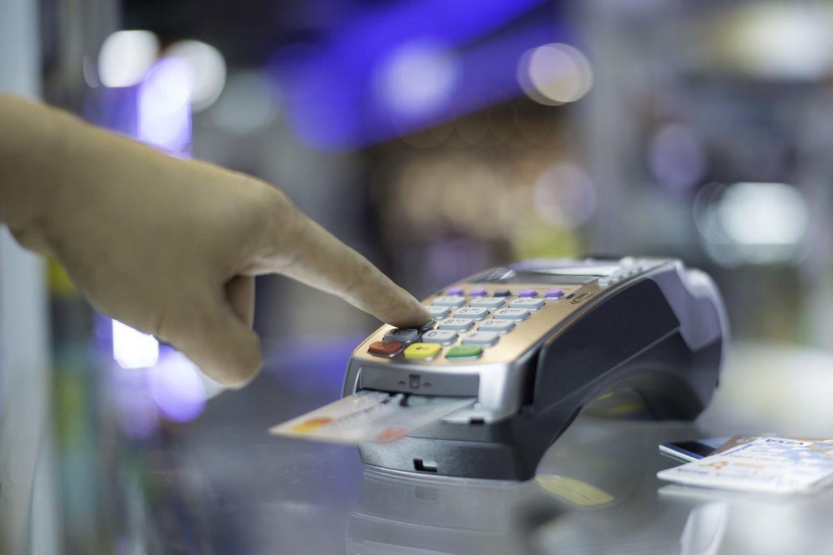 Finger entering pin number into card chip reader.