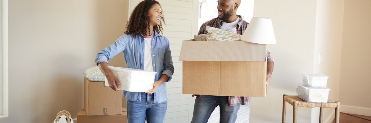 Couple happily moving boxes into new house.