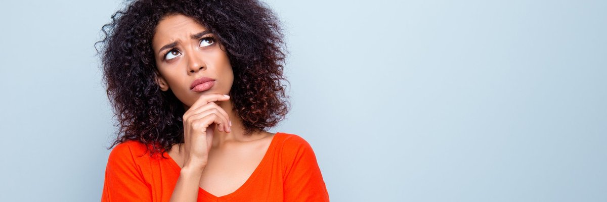 Woman standing with hand on chin contemplating her decision.