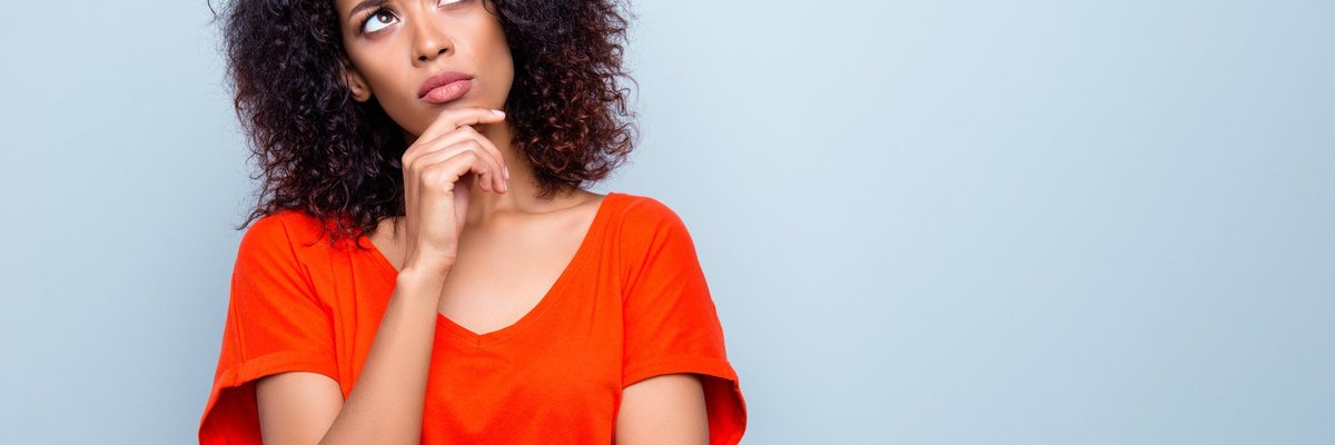 Woman standing with hand on chin contemplating her decision.