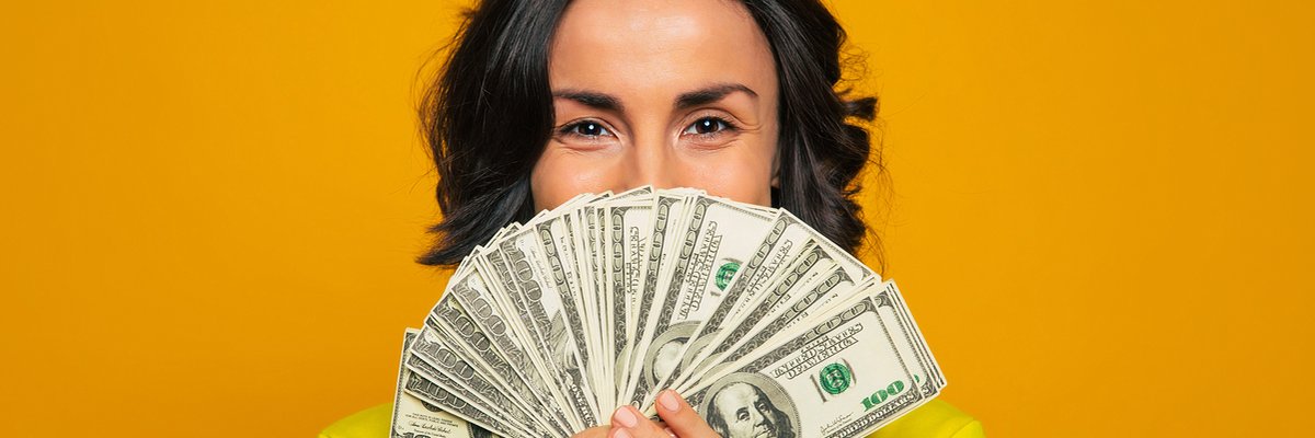 Happy woman hiding half her face with a fan of cash.