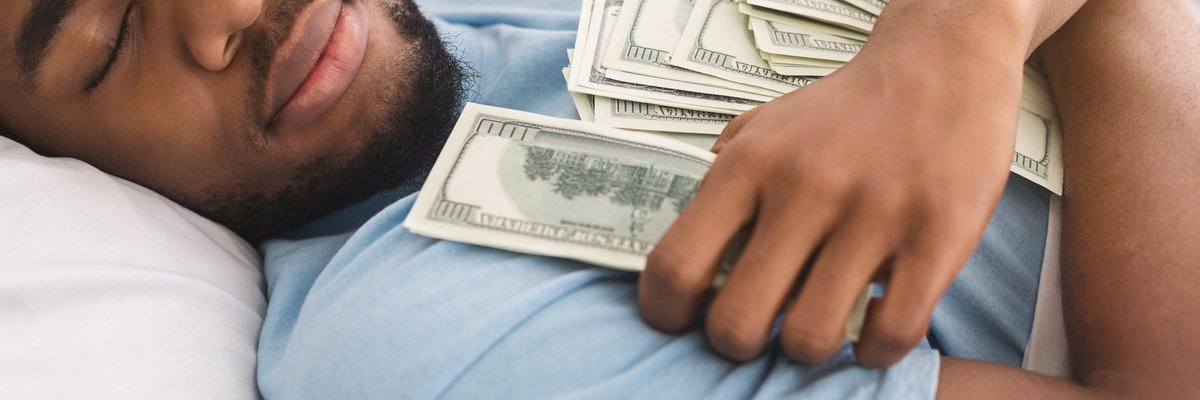 A man is sleeping contentedly while holding lots of money.
