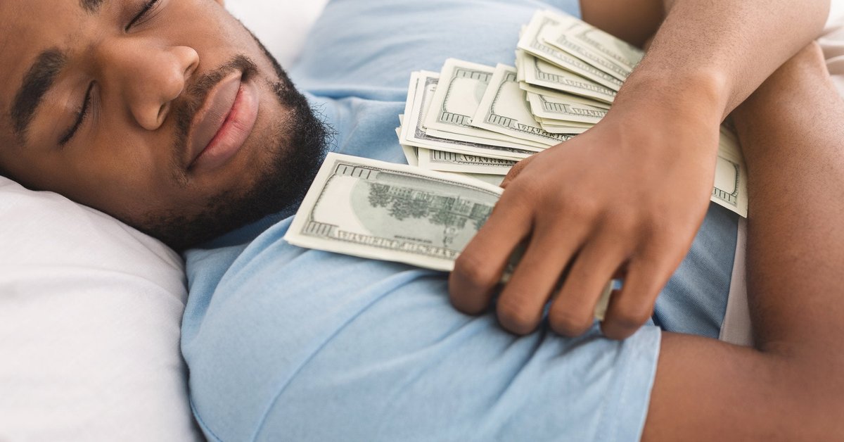 A man is sleeping contentedly while holding lots of money.