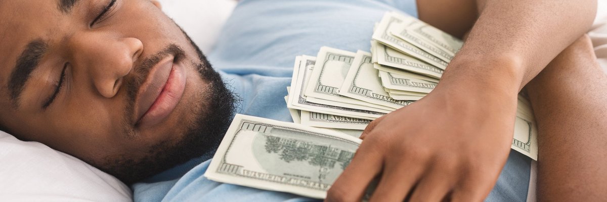 A man is sleeping contentedly while holding lots of money.