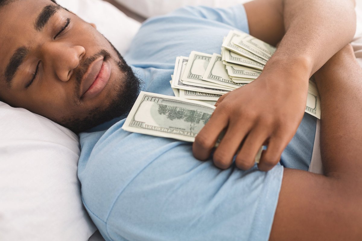 A man is sleeping contentedly while holding lots of money.