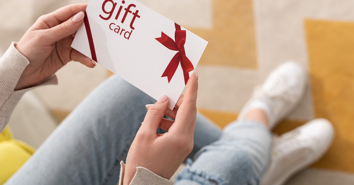 A woman holds a generic gift card.