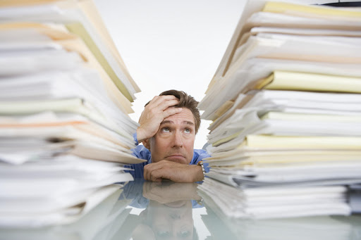 Man looking up at two piles of folders.