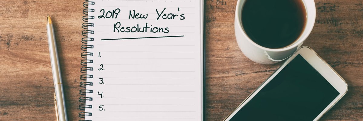 Cup of coffee, smartphone, pen, and notepad for 2019 New Year's Resolutions.