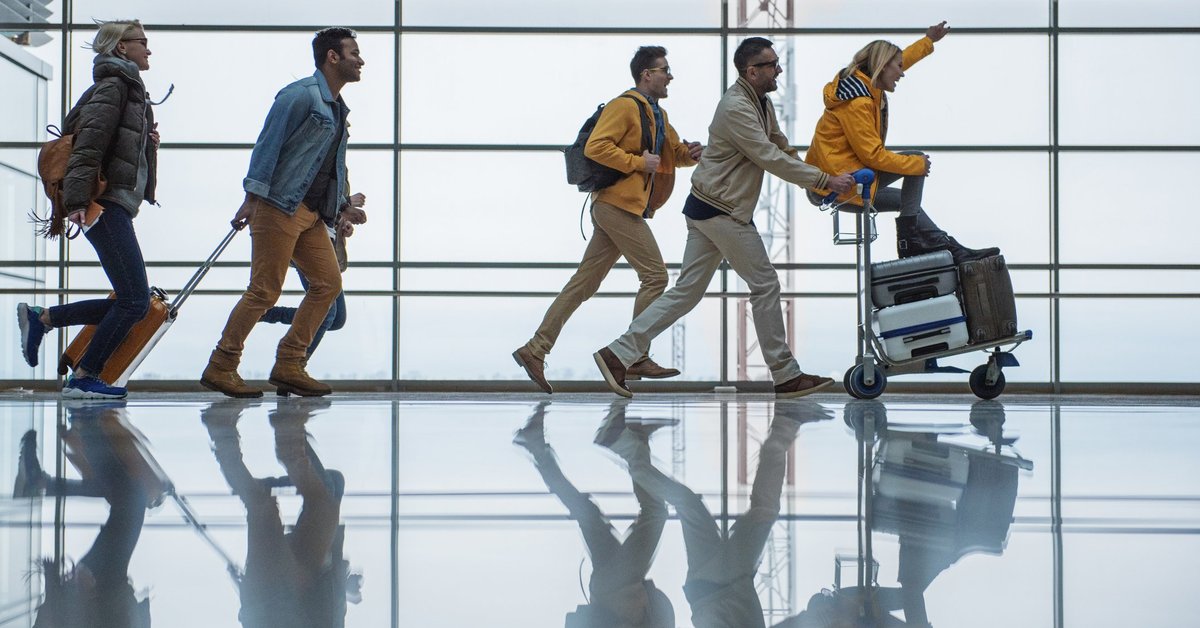 A group of friends racing through an airport with their suitcases.