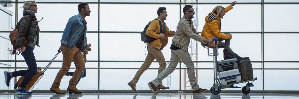 A group of friends racing through an airport with their suitcases.