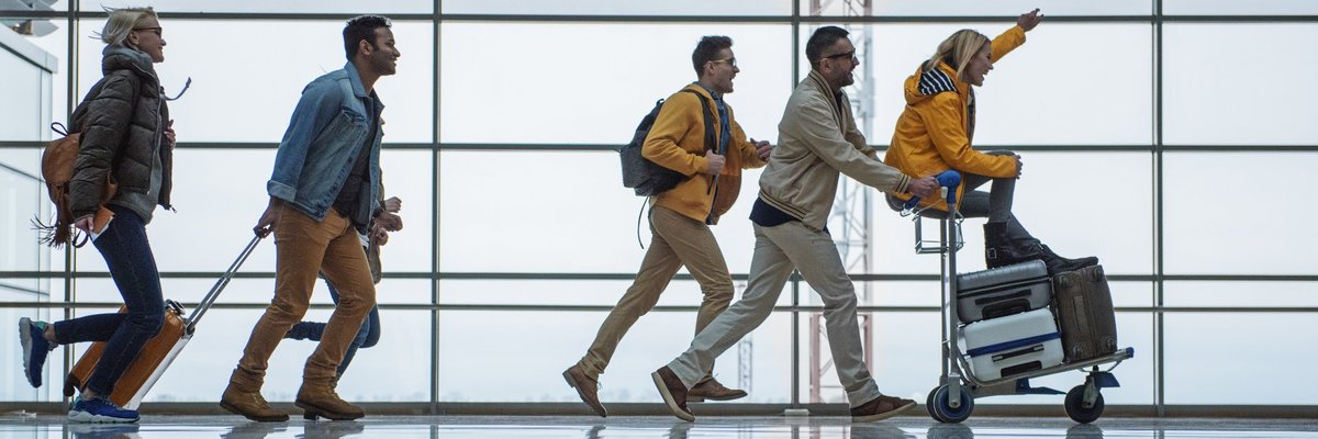 A group of friends racing through an airport with their suitcases.