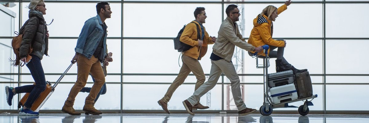 A group of friends racing through an airport with their suitcases.