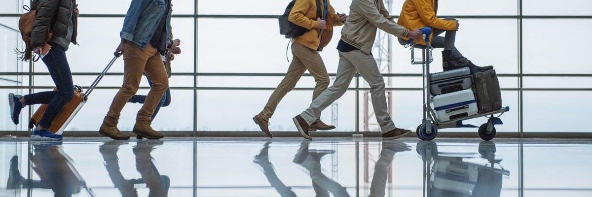A group of friends racing through an airport with their suitcases.