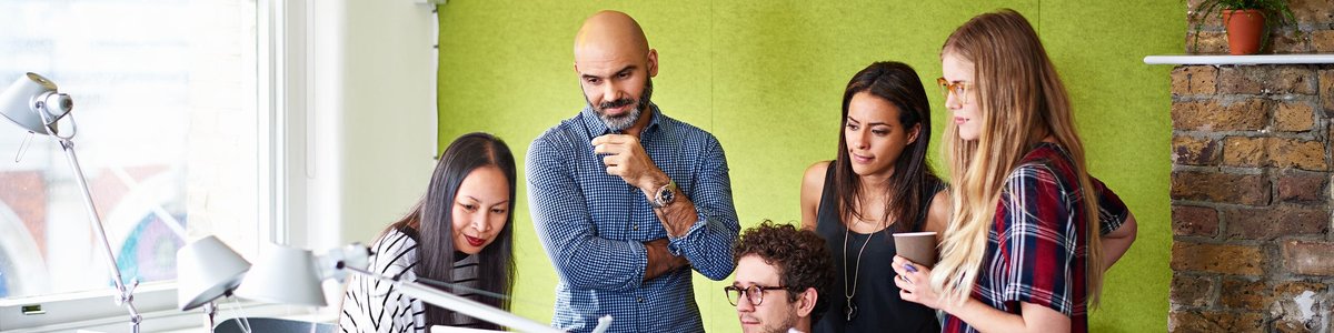 Group of people gathered looking at a computer screen.