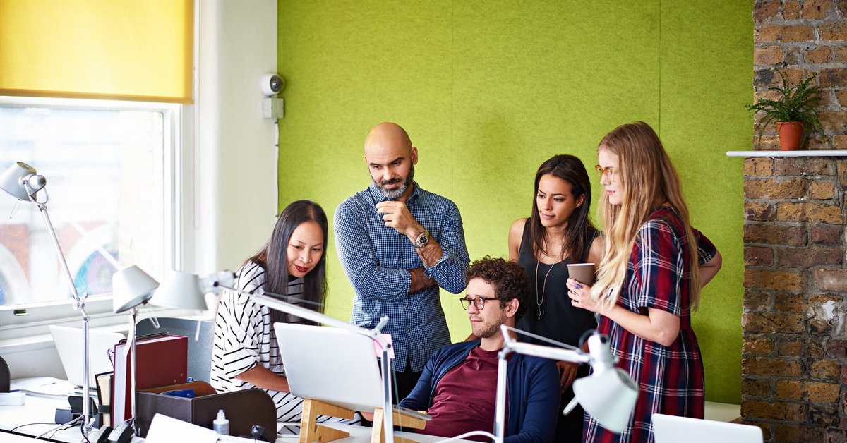 Group of people gathered looking at a computer screen.