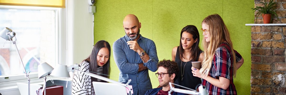 Group of people gathered looking at a computer screen.